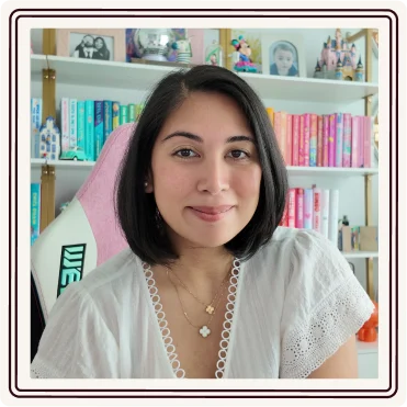 Yasmin smiling at her desk in front of a colorful bookshelf